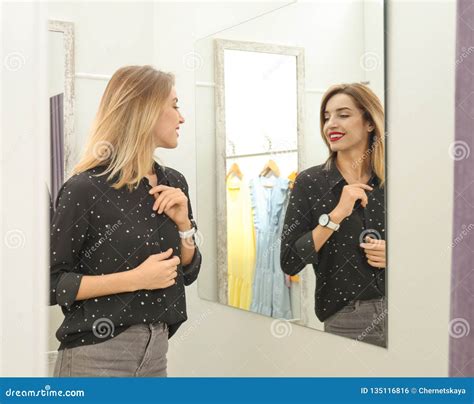 Young Woman Trying On Clothes In Dressing Room And。